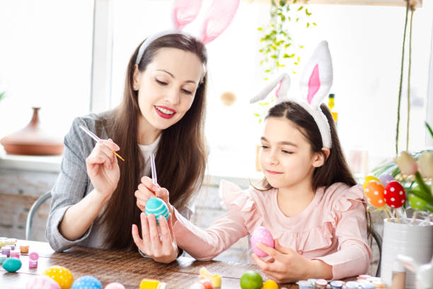 istock Mom and daughter wearing bunny ears decorating Easter eggs. 1366995185