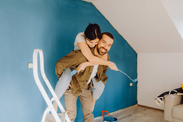 istock Young couple paint together a wall in their apartment 1366996385
