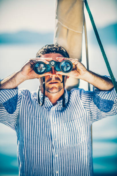 istock Handsome man with binoculars on sailboat 1366999913