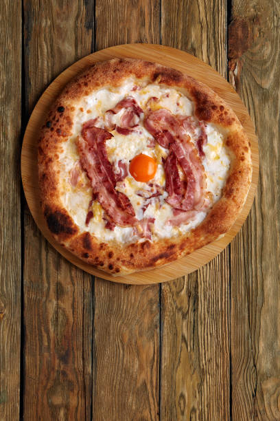 istock Carbonara pizza with bacon and egg on wooden background 1367001134