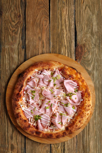 istock Fresh pizza with ham and pineapple on wooden table in restaurant 1367001155
