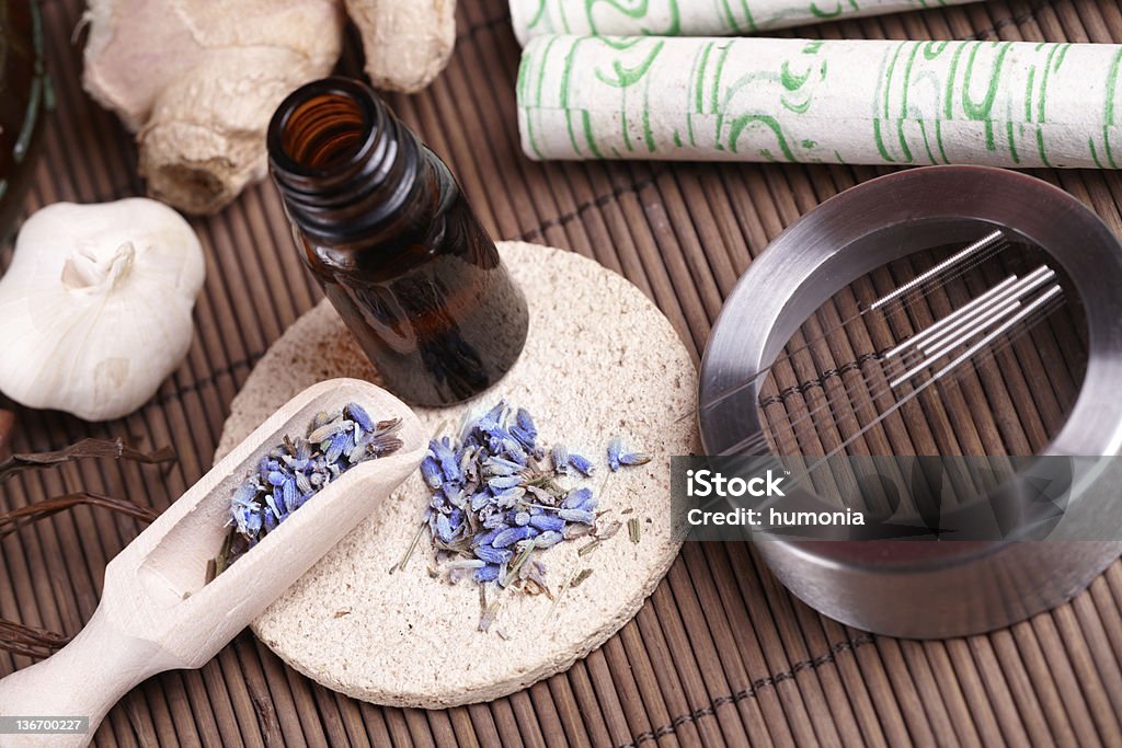 Acupuncture needles, moxa sticks and TCM herbs Acupuncture needles laying on the stone mat, moxa sticks on wooden desk and lavender petals with macerated oil. TCM Traditional Chinese Medicine concept photo Acupuncture Stock Photo