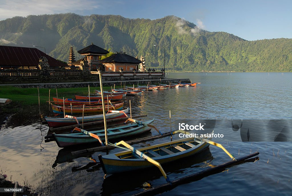Lake Bratan with outrigger canoes at Pura Ulun Danu, Bali Traditional boats, prahu, at Lake Bratan in Bali. In the background the multitiered roofs of Pura Ulun Danu. Lake Bratan is nestled high in the cool volcanic mountains of Bali. Lake Bratan Stock Photo