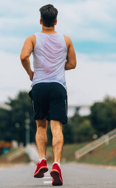 istock Young man in sportswear jogging outdoors on running track 1367005716