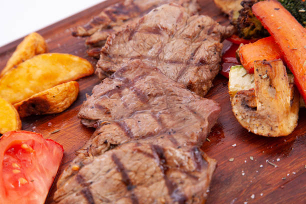 istock Grilled beef steaks and vegetables on wooden board 1367006123
