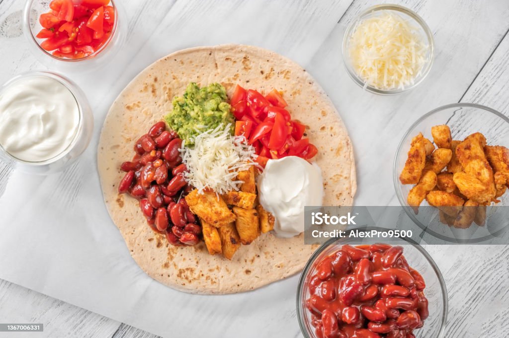 Taco with filling on the wooden background Taco with chicken and vegetable filling on the wooden background Sour Cream Stock Photo