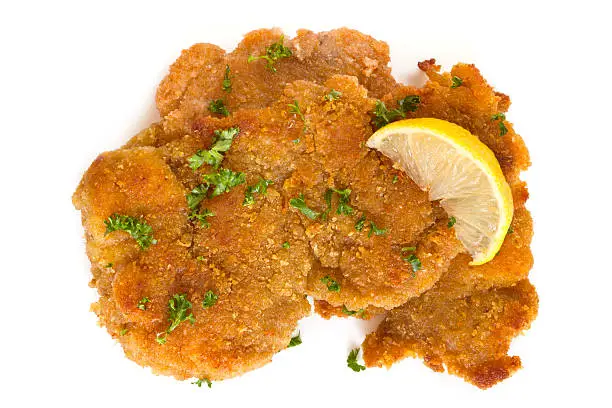 Schnitzel, garnished with lemon and parsley, isolated on white.