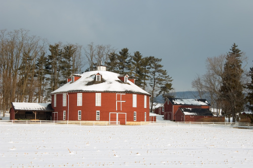 A round barn in a white winter landscape, agriculture in rural countryside, Pennsylvania, PA, USA.