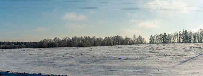 Winter farmland scenery landscape under snow with trees on background. Winter landscape with snow covered countryside. Space for text.
