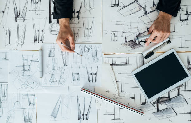istock Table Top View of Designer Hands Drawing Blueprint Design at Design Studio 1367015523