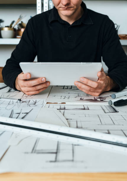 istock Close Up Photo of Architect Hands Holding Digital Tablet and Looking Construction Project in his Office 1367015529