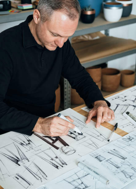 Handsome Designer Working on a Project in his Office Serious furniture designer sketching drawing design of plant stand at his workplace. industrial designer stock pictures, royalty-free photos & images