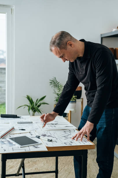 istock Serious Architect Working on an Architectural Drawing for Home Renovation 1367015555