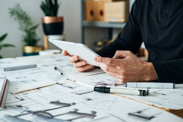 istock Close Up Photo of Architect Hands Holding Digital Tablet and Looking Construction Project in his Office 1367015562
