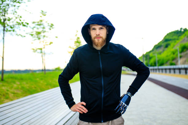 man with arm prosthesis in sports clothing ready for morning workout outdoors. disabled sport concept - paralympic games prosthetic equipment amputee athlete imagens e fotografias de stock
