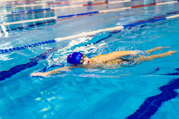 menino deficiente com síndrome de down em boné de natação usando óculos na piscina - boia equipamento de desporto aquático - fotografias e filmes do acervo