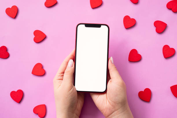 istock Valentine's day concept, mobile phone in hand blank screen with red hearts on pink background. Love in social media 1367015992