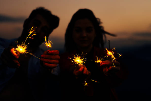 istock Young silhouette couple having fun with some firecracker at mountain 1367016488