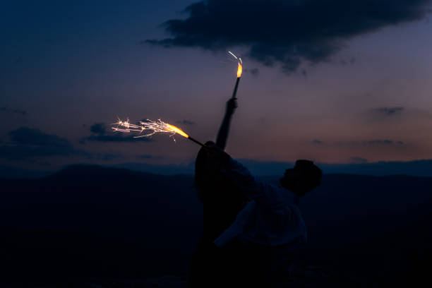 istock Happy silhouette couple dancing with firesticks at open air under sunset sky 1367016546