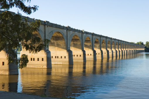 Long bridge arches disappearing into vanishing point, a railroad crossing the Susquehanna River at Harrisburg, Pennsylvania, PA, USA.