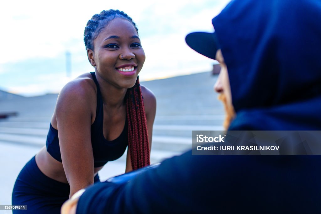 spain woman with afro pigtails gym trainer motivating her boyfriend for morning running outdoors in sity spain woman with afro pigtails gym trainer motivating her boyfriend for morning running outdoors in sity . Adult Stock Photo
