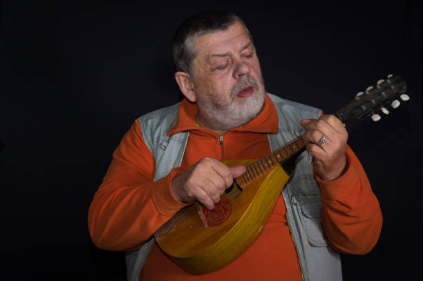 zurückhaltendes porträt eines kaukasischen seniormusikers, der mandoline spielt - mandoline stock-fotos und bilder