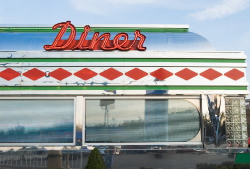 Diner with sign in bright red neon and chrome, 1950's retro style restaurant, vintage roadside Americana, USA.