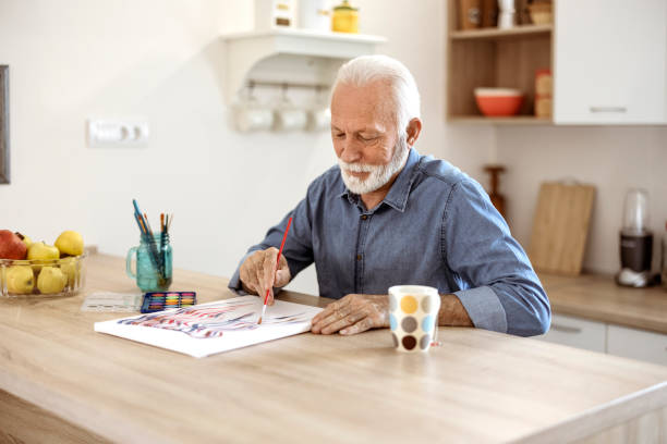 istock Senior man painting on a canvas in the kitchen 1367021201