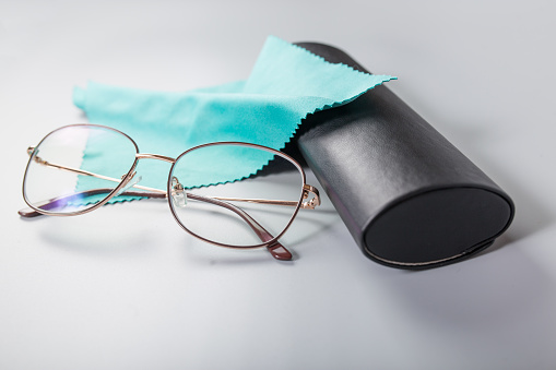 Glasses  for reading with blue napkin and black case, close up on grey background.