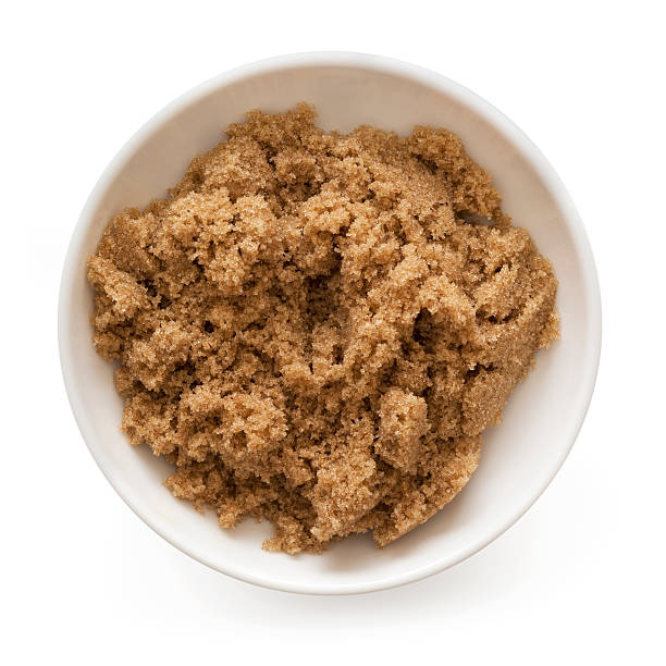 A white bowl of brown sugar on a white background