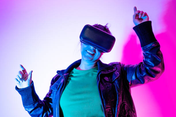 istock Woman with virtual reality goggles dancing in metaverse 1367025965