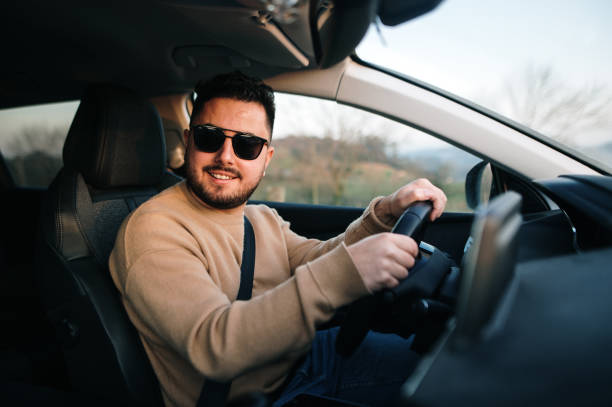 istock Young man with sunglasses driving a car 1367028684