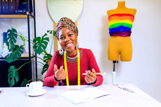 뱀 프린트 터번을 가진 탄자니아 여성은 드레스 메이킹 쇼룸에서 프라이드 퍼레이드를위한 다채로운 드레스를 만드는 것을 듣습니다. - homosexual gay pride business rainbow 뉴스 사진 이미지
