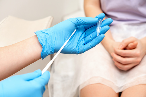 The gynecologist takes a sample of biomaterial from the patient's urogenital tract for PCR examination,hands close- up.Women's health, medical concept.