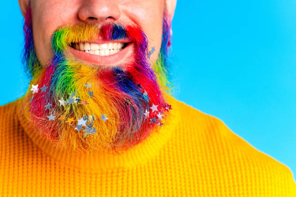 istock handsome man with raindow in beard with glitter confetti in blue studio baclground 1367030445