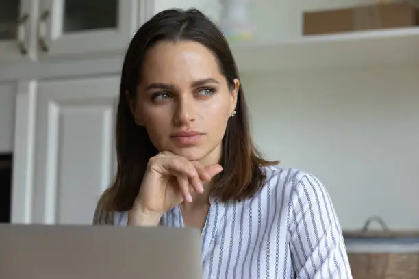 Photo of Serious pensive millennial business professional woman distracting from work