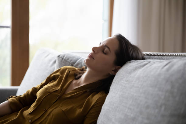 istock Tired millennial young woman sleeping in sitting position on couch 1367031491