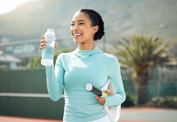 shot of a sporty young woman drinking water while playing tennis outdoors - tennis women one person vitality imagens e fotografias de stock