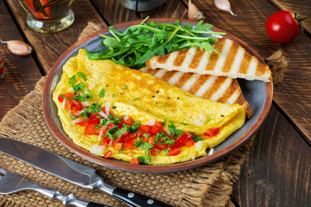 istock Fried omelette with tomatoes, onion and herbs. Delicious breakfast with eggs and toasts 1367033272
