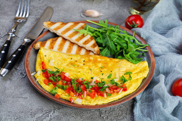 istock Fried omelette with tomatoes, onion and herbs. Delicious breakfast with eggs and toasts 1367033278