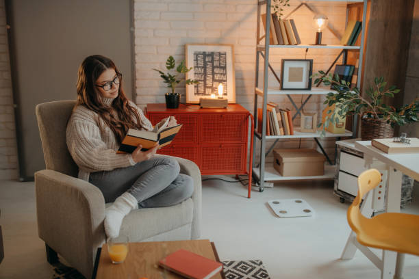 istock Woman reading a book at home 1367038509