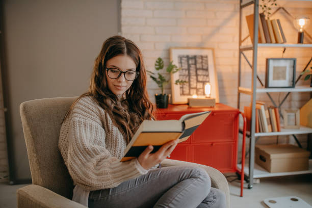 istock Woman reading a book at home 1367038751