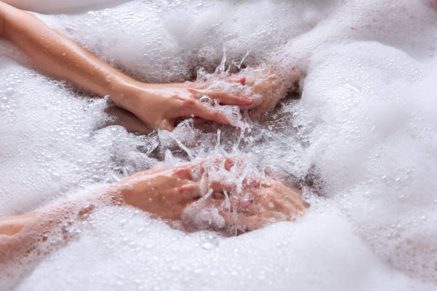 vue rapprochée des mains d’un couple amoureux prenant un bain avec de la mousse blanche. - soaking tub photos et images de collection