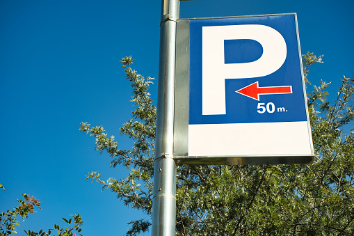 Parking symbol indicating the direction and the distance to it. Blue sky background.