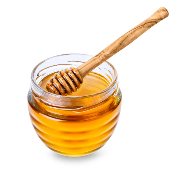 istock Glass jar with honey and honey dipper on white background 1367044843