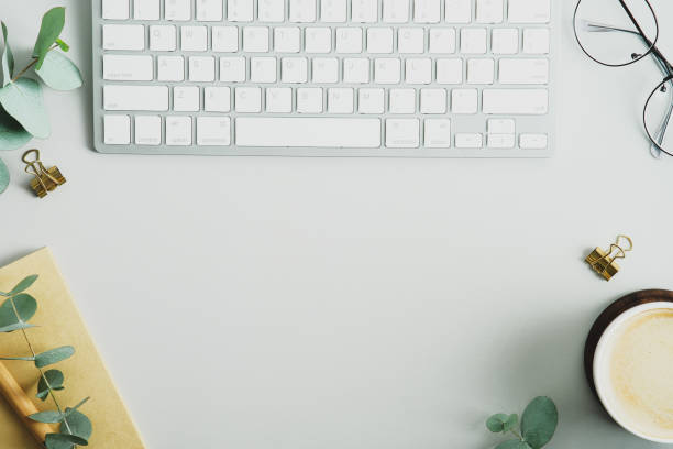 istock Office desk table with keyboard, coffee cup, eucalyptus branches and office supplies. Elegant feminine workspace top view. Flat lay, overhead. 1367048361