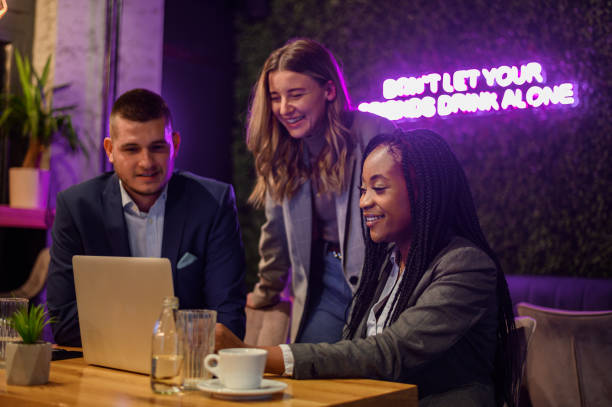 istock Cheerful work colleagues working on a laptop while having a meeting in a cafe 1367048687