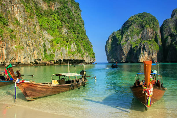 タイ・クラビ県ピピリー島のマヤ湾に停泊するロングテールボート - thailand beach longtail boat cliff ストックフォトと画像