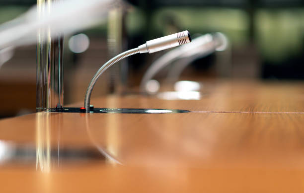 istock Isolated microphone with intercom system on a table in a conference room among blurred other mics in the background - close-up with selective focus 1367053047