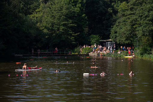 London, UK - September 05 2022: People enjoying swimming in the mixed bathing pond in Hampstead Health Lido on a warm summer day